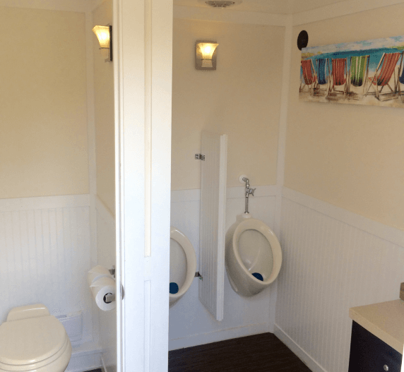 Portable restroom interior with two urinals, one toilet, and white walls.
