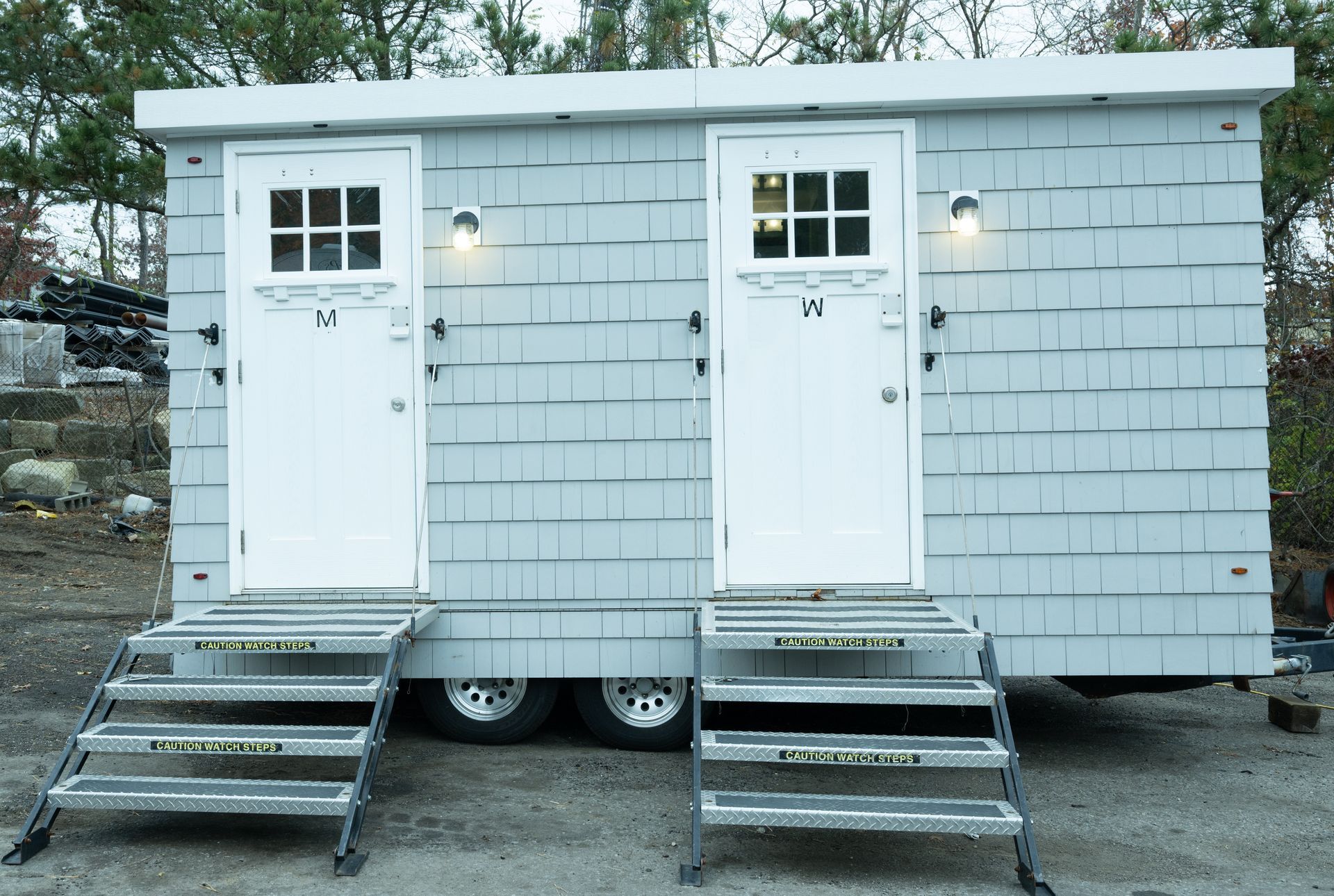 Two light blue portable restroom stalls with white doors and metal steps.
