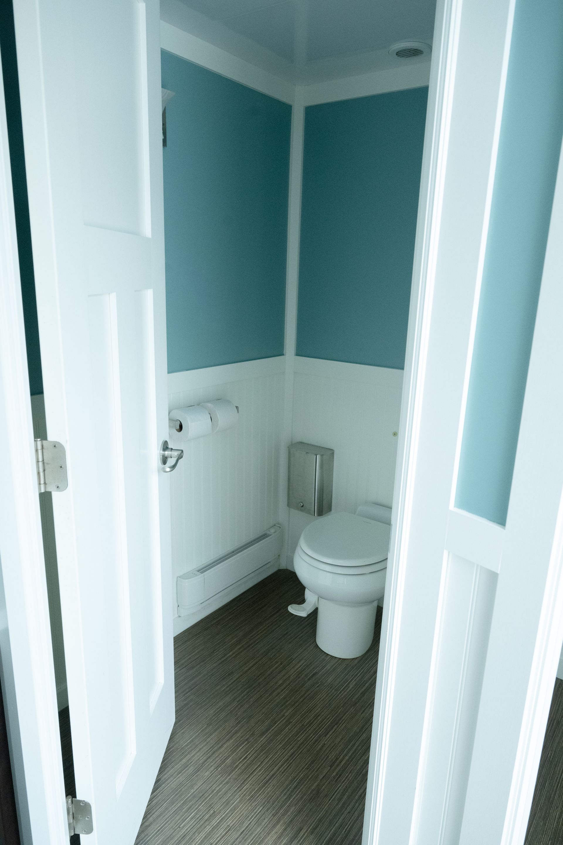 Small bathroom with white trim, blue walls, and a toilet.