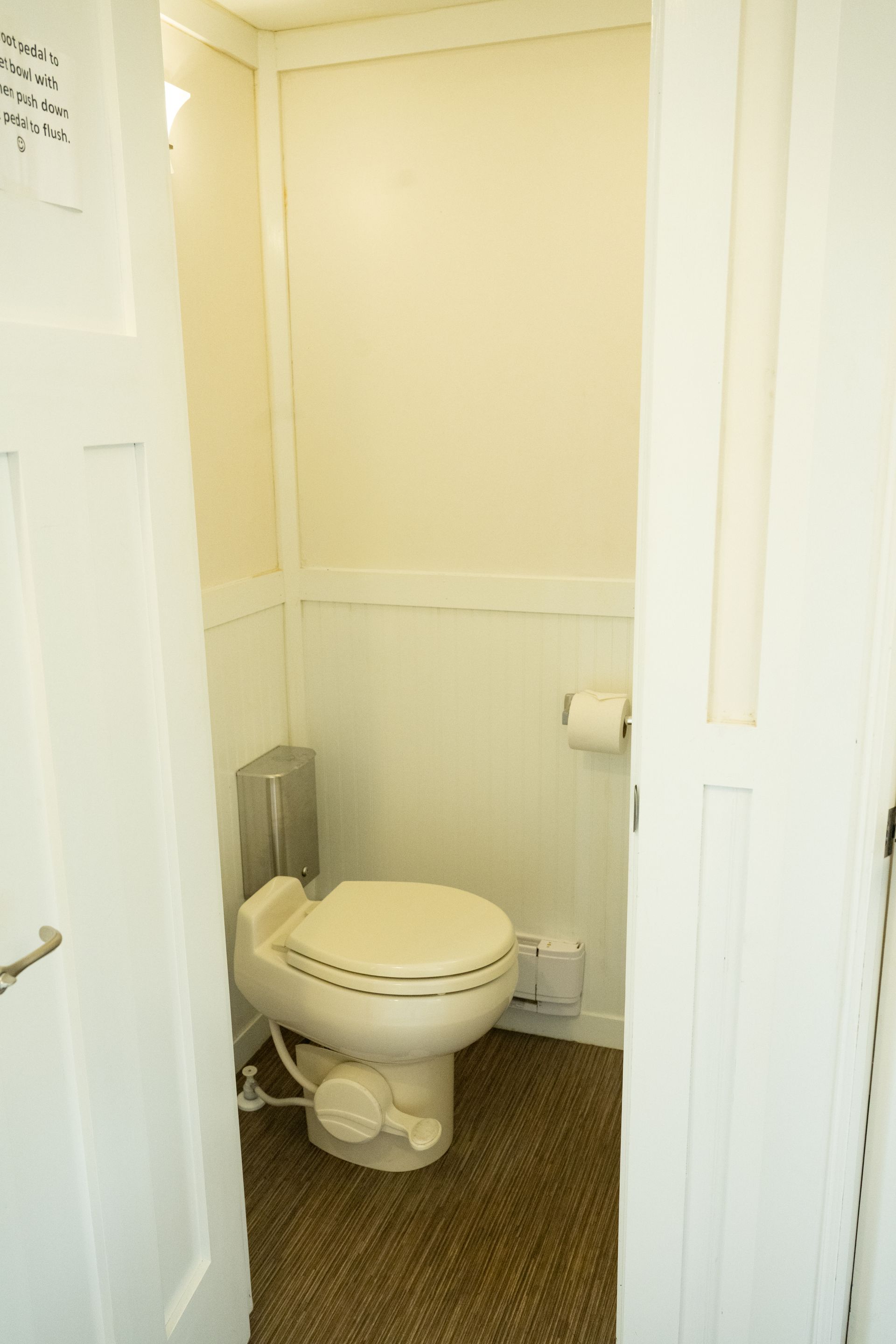 Small, white-walled bathroom with a toilet. Door open. Brown carpet.