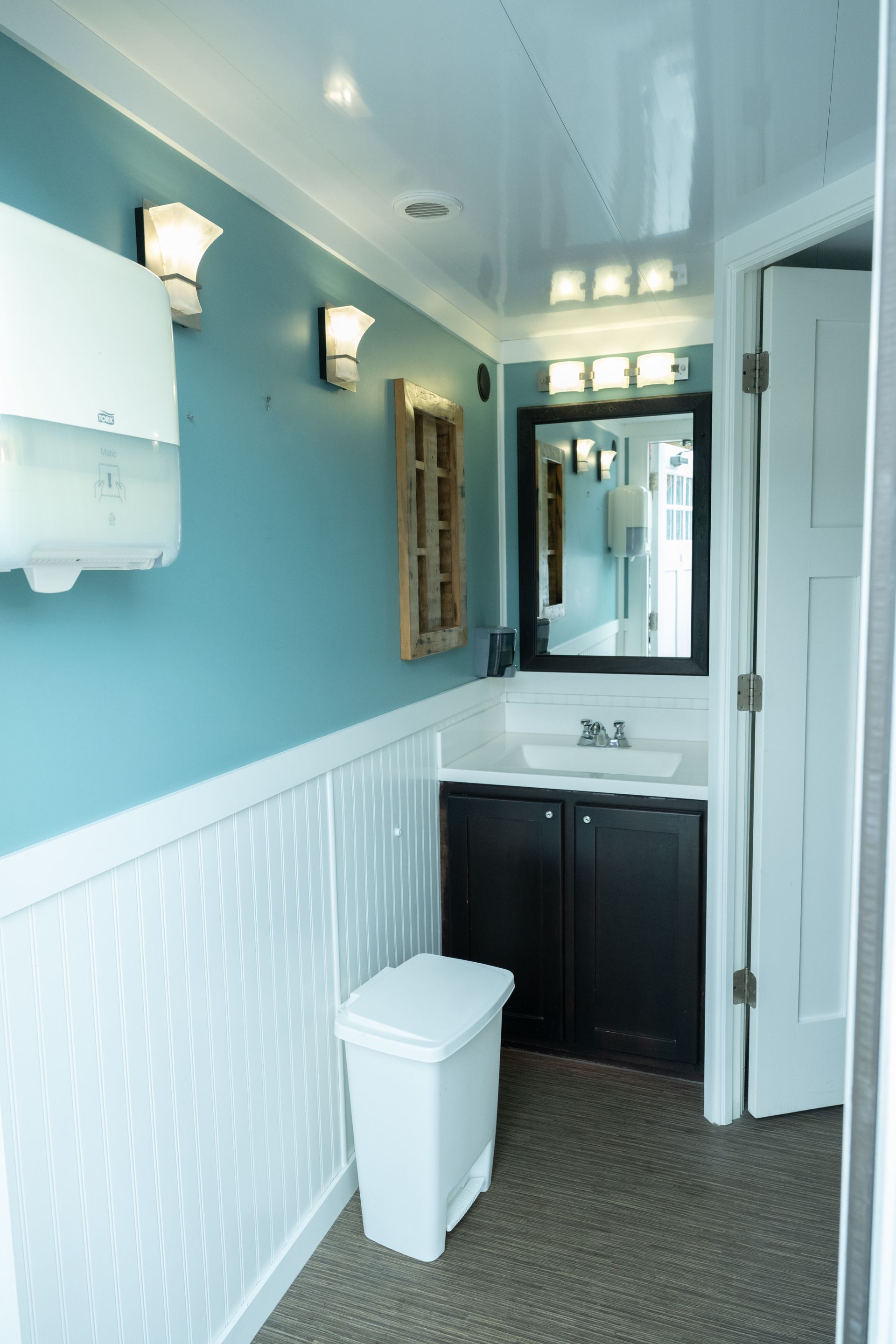 Interior of a restroom with blue and white walls, sink, mirror, and toilet.