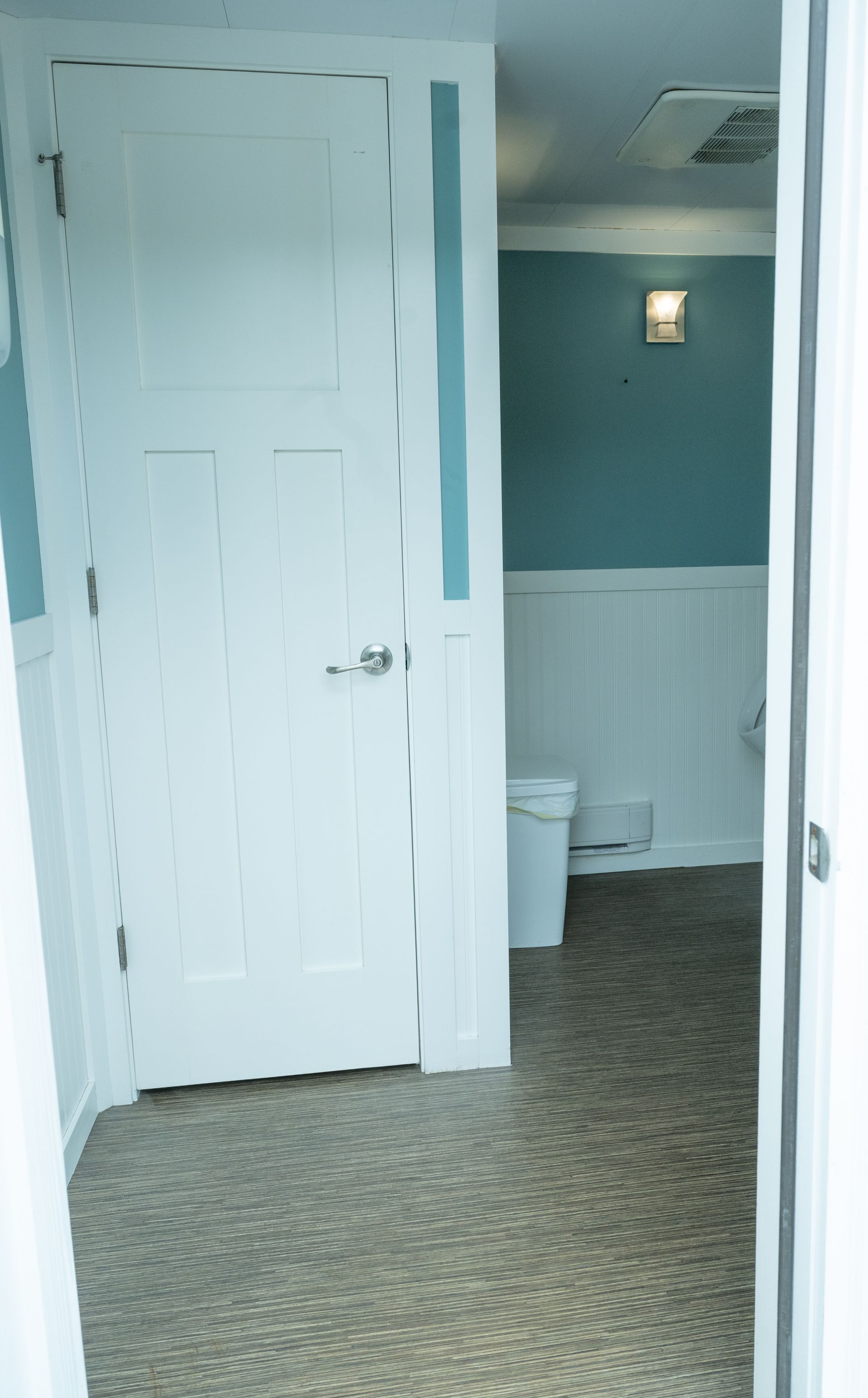 White door opens to a bathroom with blue walls and a toilet.