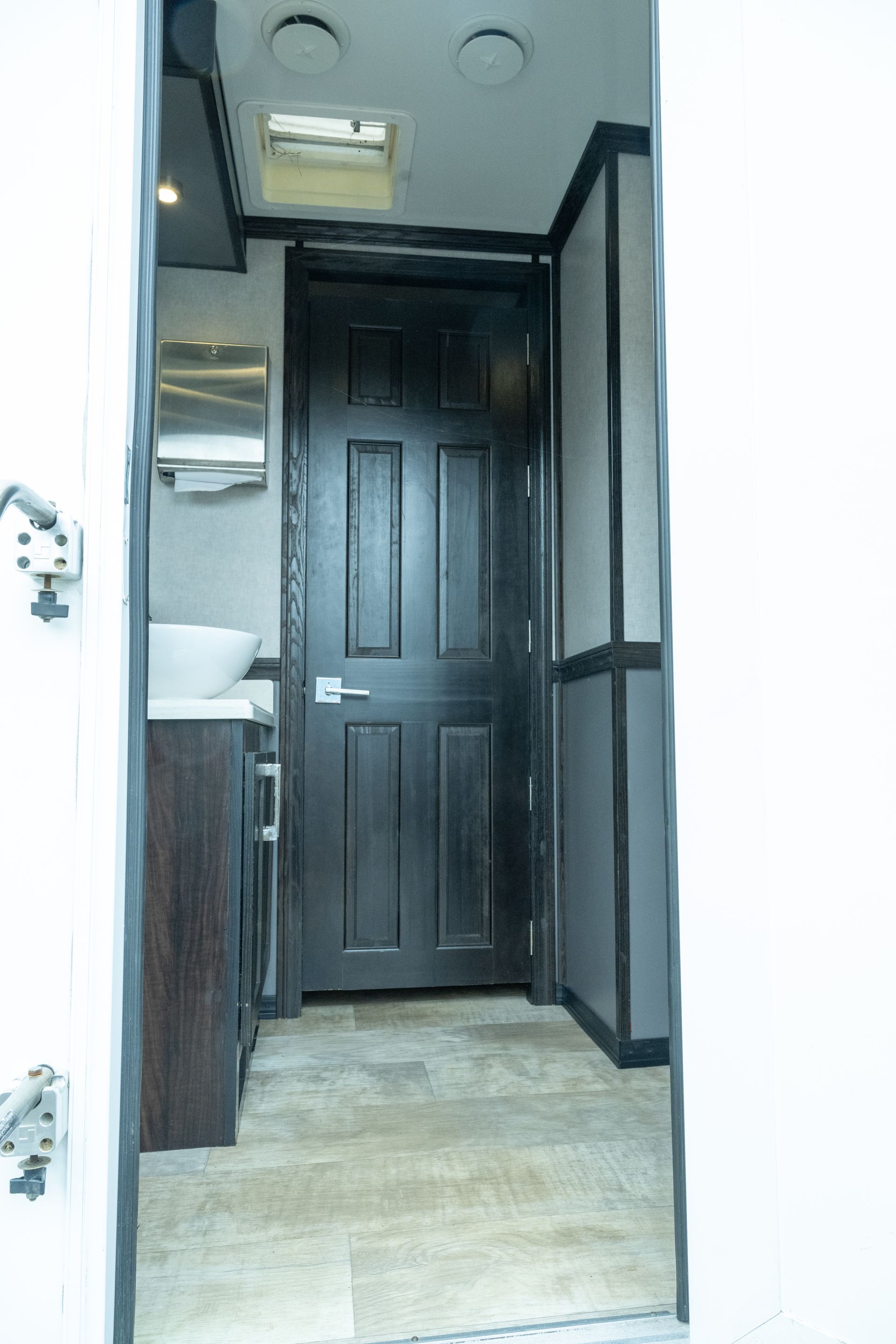 Interior view of a bathroom with a dark wooden door and a sink area.