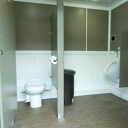 Accessible restroom with toilet stalls, a toilet, sink, trash can, and brown-and-white walls