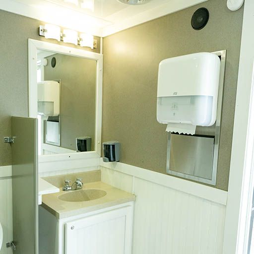 Small restroom with sink, mirror, and wall-mounted paper towel dispenser in neutral tones.