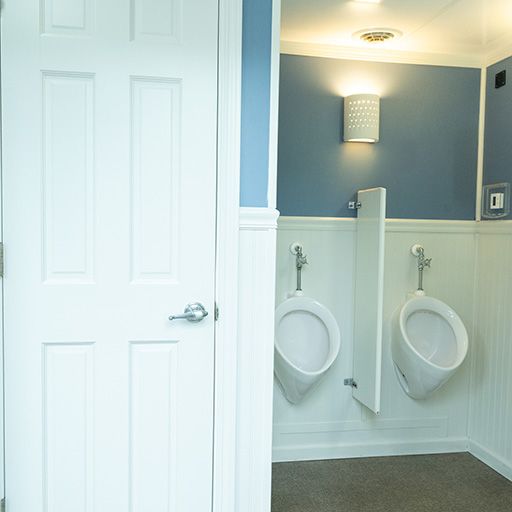 Modern bathroom with two wall-mounted urinals, white wainscoting, and blue walls