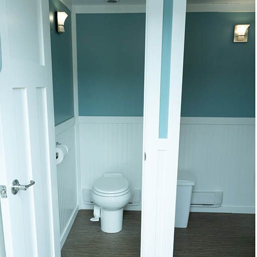 Small bathroom with teal walls, white wainscoting, and a toilet between two open doors.