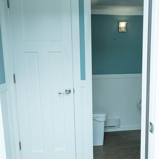 Bathroom doorway with white door, teal walls, and white wainscoting visible inside