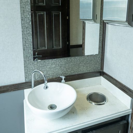 Modern bathroom vanity with white vessel sink, chrome faucet, and round inset trash opening