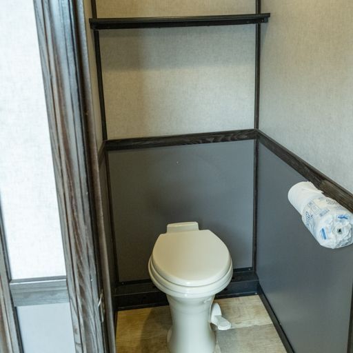 Small accessible bathroom stall with a toilet and grab bars, plus a toilet paper dispenser on the wall