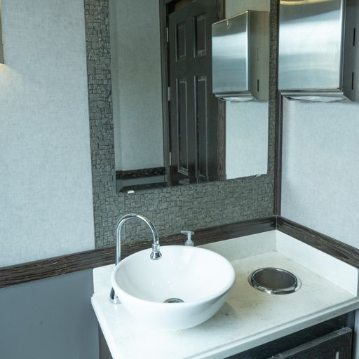 Modern restroom sink with white vessel basin, chrome faucet, and mirror above counter