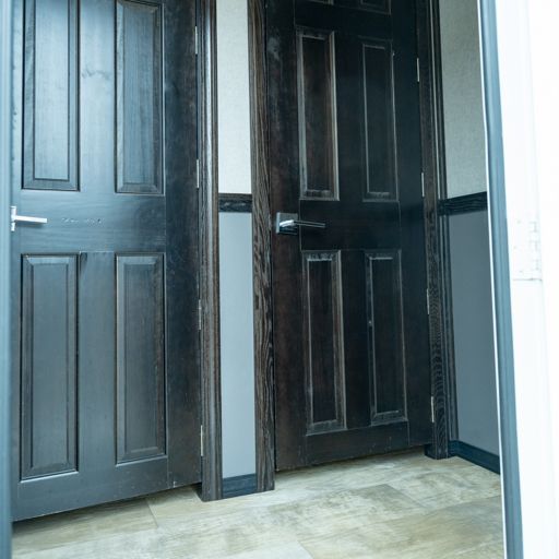 Two dark wooden doors in a hallway, one open and one closed, with beige tile floor