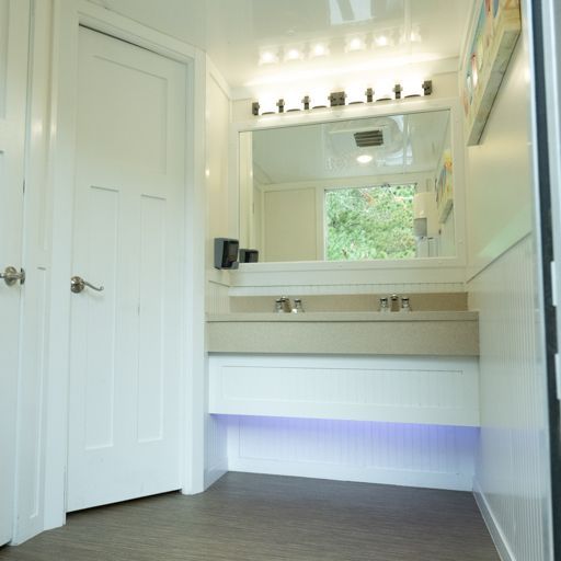Bright bathroom vanity with mirror, white cabinets, and a blue-lit space beneath the sink