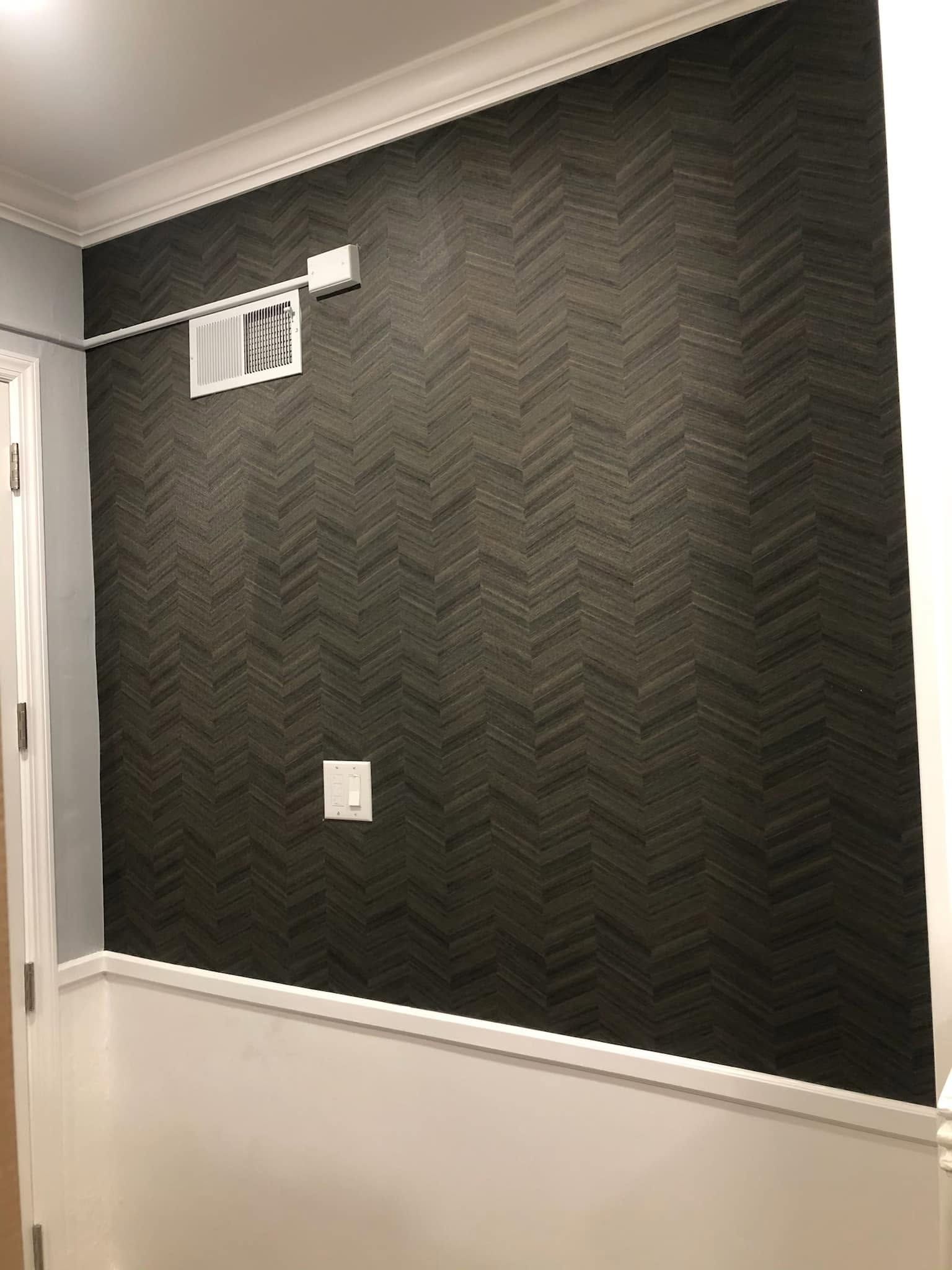 Dark textured accent wall with white trim and a small wall vent in a hallway.
