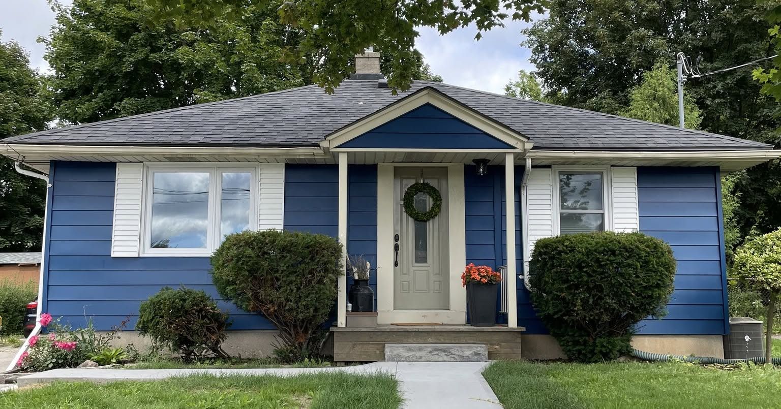 Blue single-story house with white trim, front porch, and landscaped yard