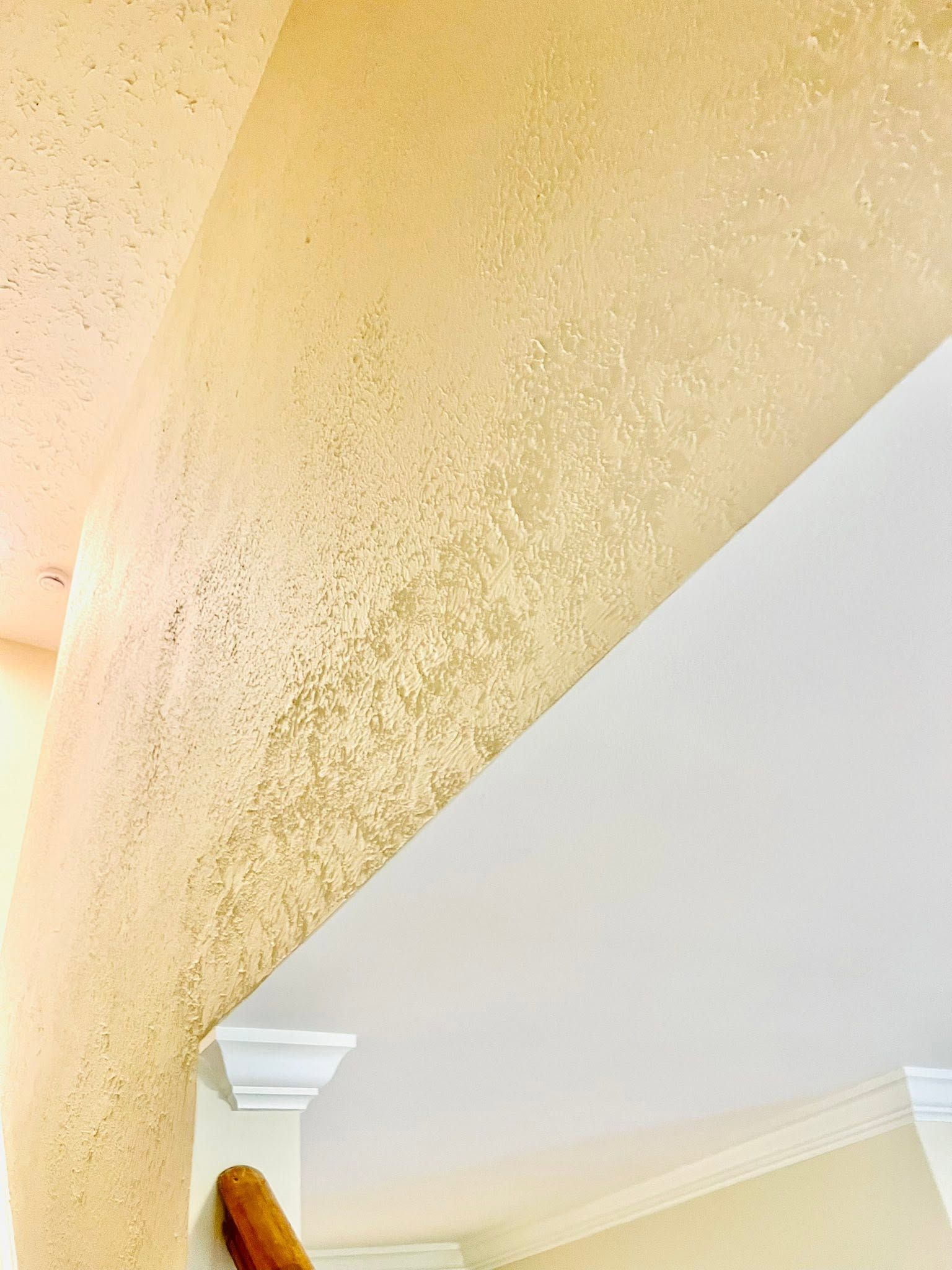 Curved beige stairwell wall with textured paint and white ceiling trim