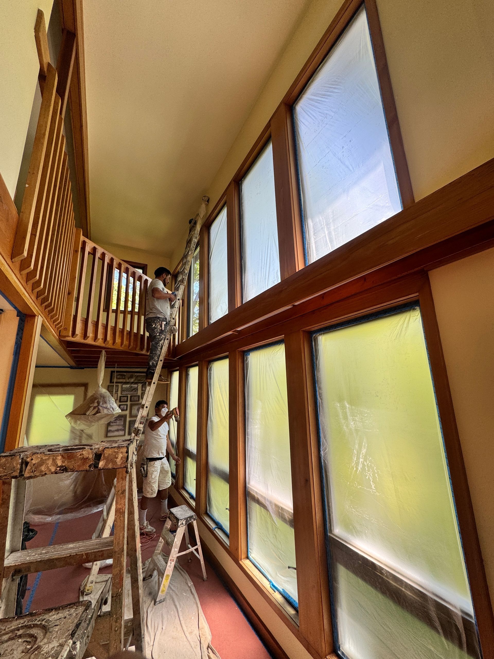 Narrow staircase with scaffolding beside large windows in a bright indoor hallway