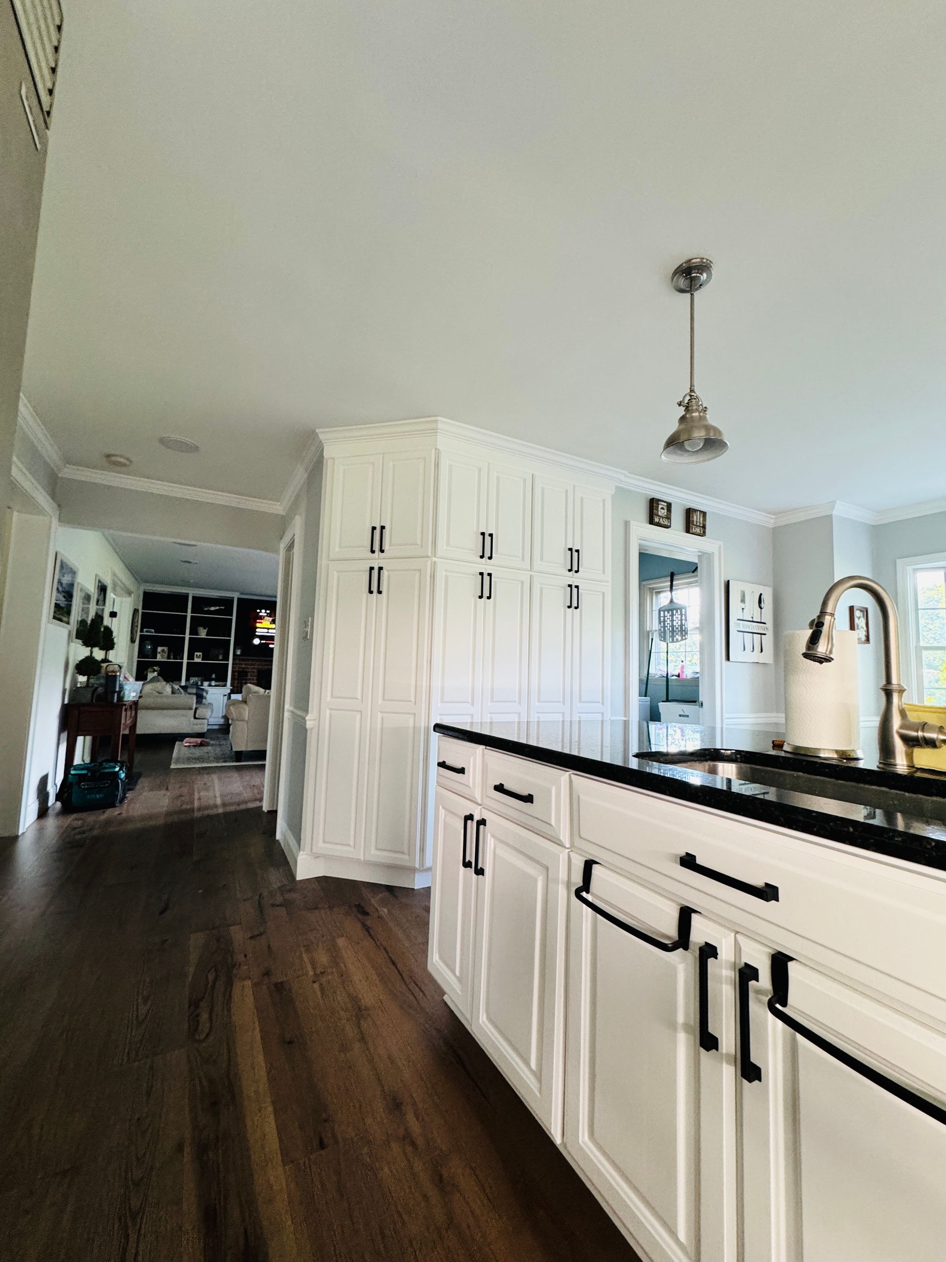 Bright kitchen with white cabinets, dark wood floor, black island countertop, and a stainless refrigerator
