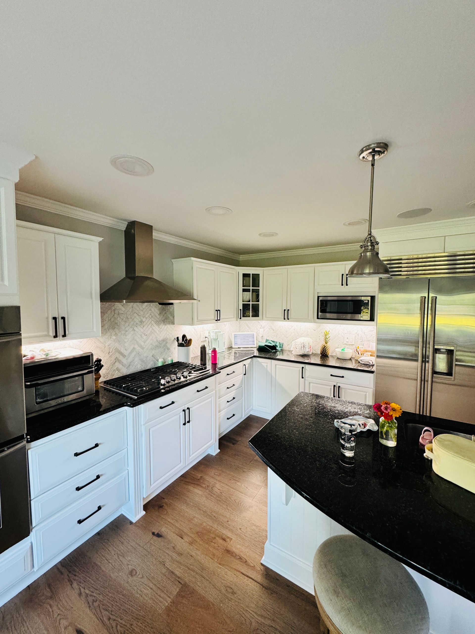 Bright modern kitchen with white cabinets, black countertops, stainless appliances, and a central island.