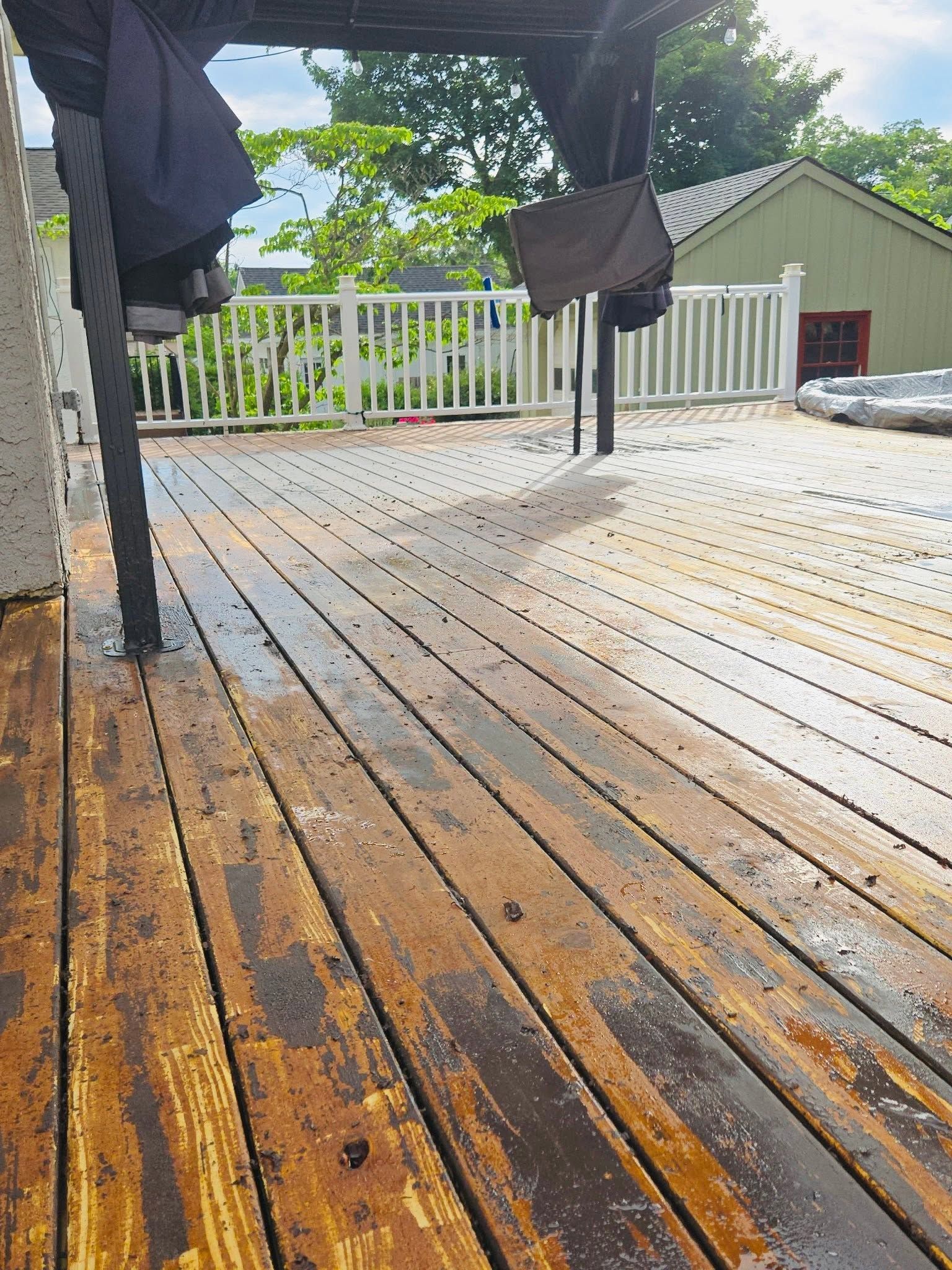 Wet wooden deck with hanging clothes, white railing, and a house in the background.