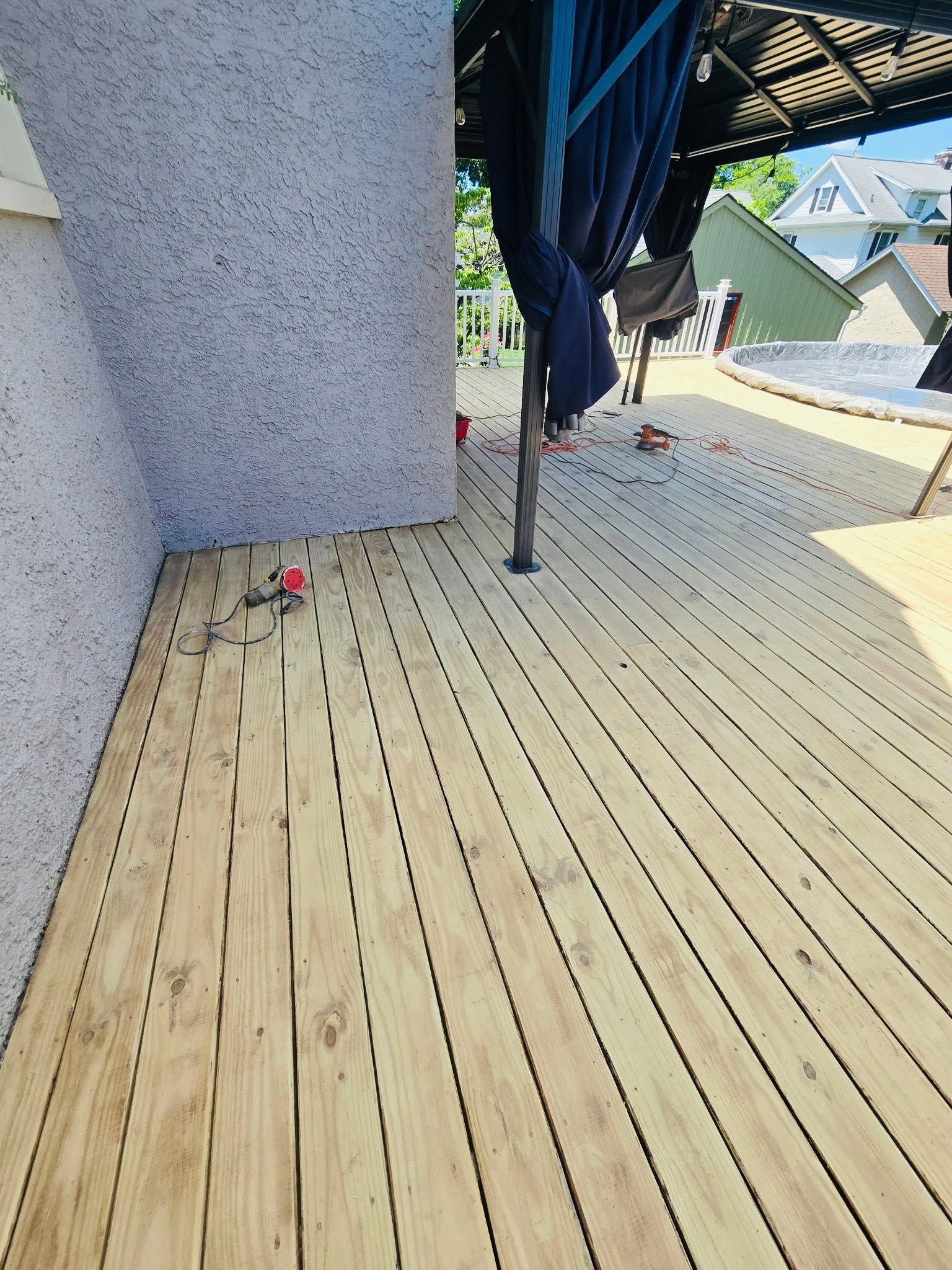 Wooden deck beside a stucco wall with a folded blue umbrella and a hanging rod base.