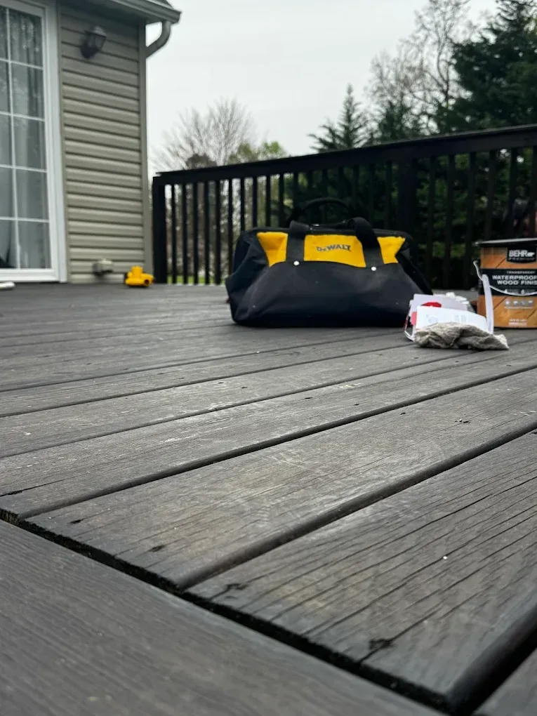 Gray deck with a black-and-yellow bag, a white bag, and a small box near the railing.