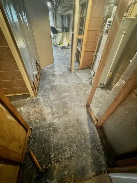 Narrow hallway with exposed walls and dusty floor, showing renovation or demolition in progress