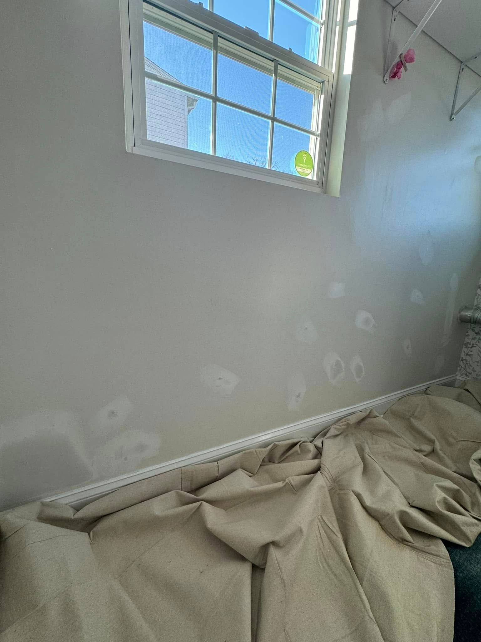 Small room with white walls, a window, and a crumpled drop cloth or tarp on the floor near the baseboard.
