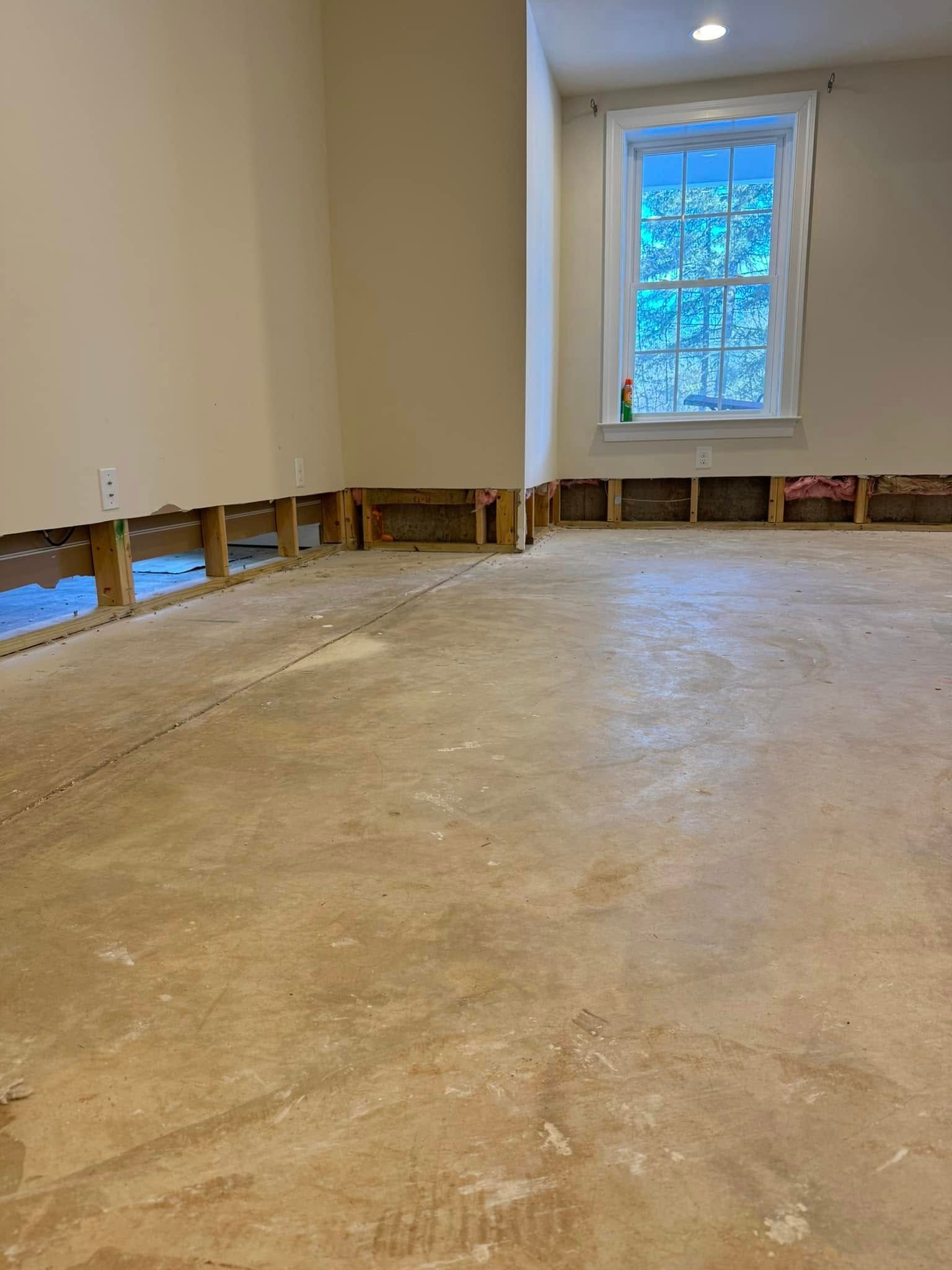 Empty room under renovation with exposed floor edges and a window letting in daylight
