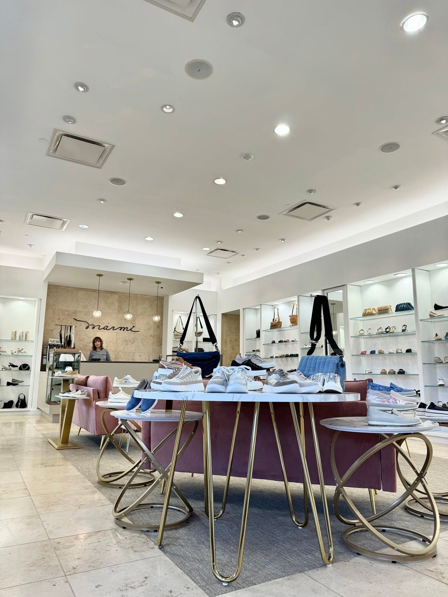 Bright clothing boutique interior with tables of folded clothes and shoes under ceiling spotlights