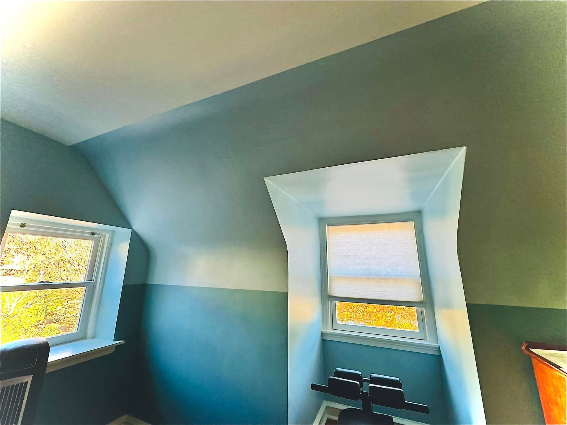Blue room with two windows and a small black table beneath the center window.