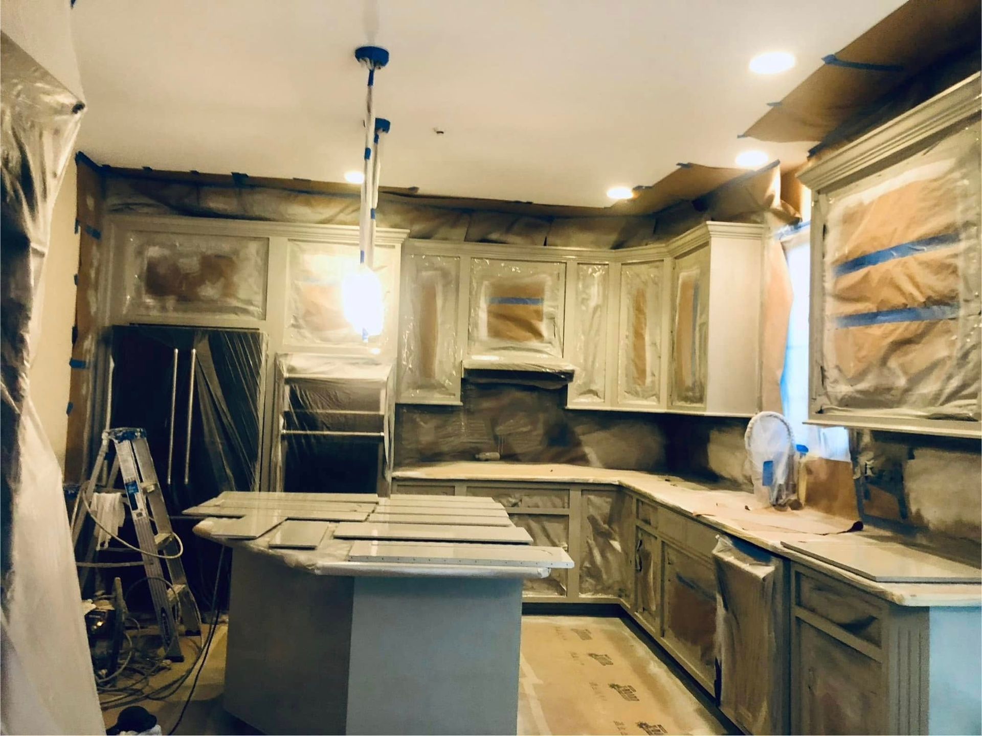 Kitchen under renovation with unfinished cabinets, covered windows, and a central work island