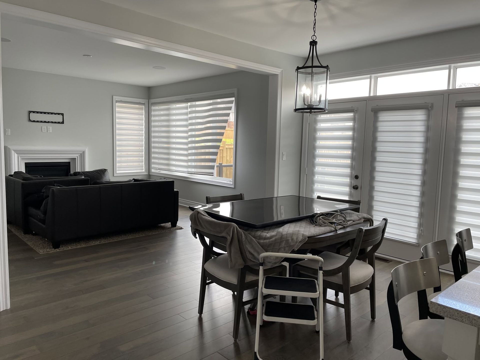 Bright dining room with dark table, black sofa, and large windows with white shutters