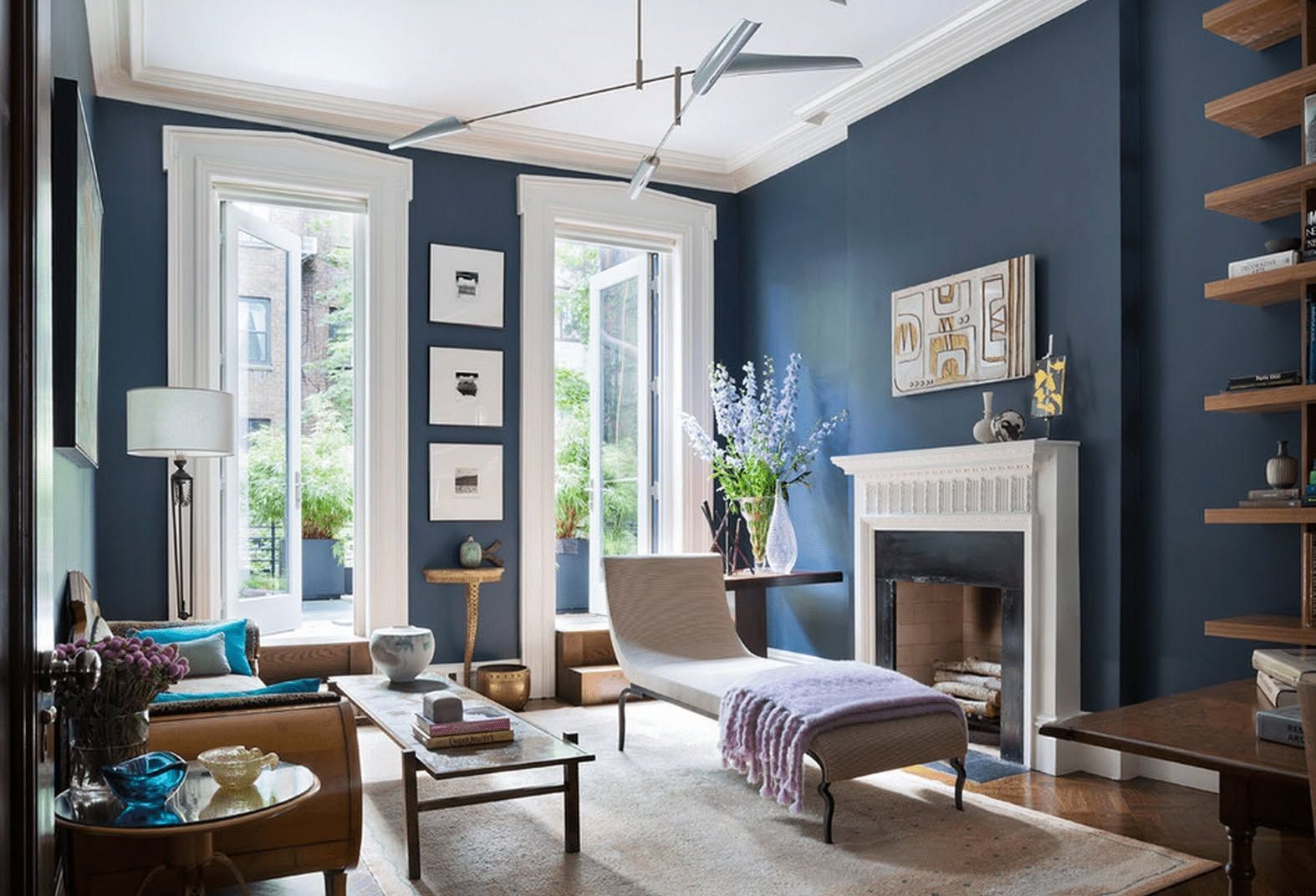 Elegant living room with blue walls, white fireplace, tall windows, and modern furniture