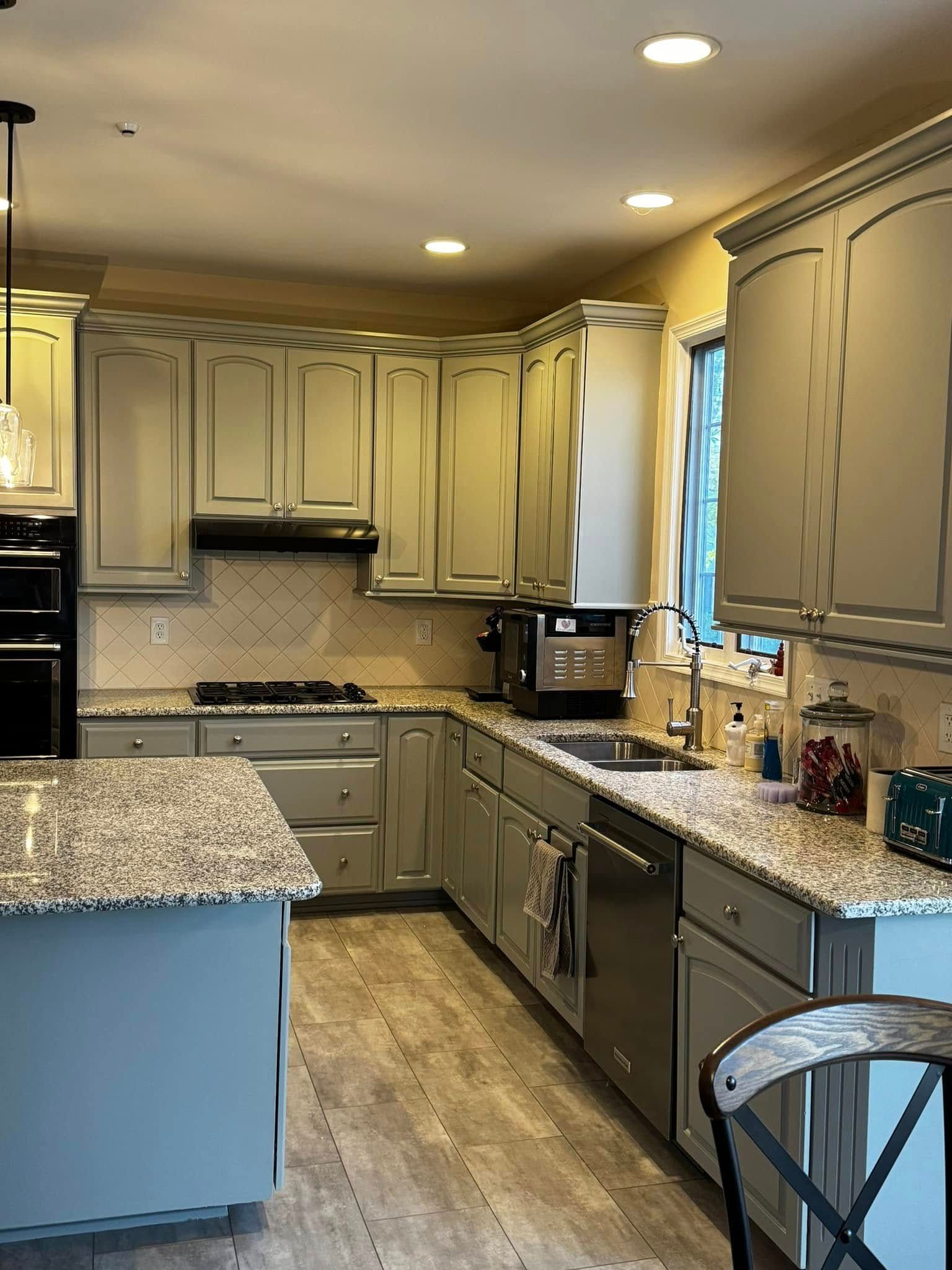 Modern kitchen with beige cabinets, granite countertops, stainless appliances, and a window over the sink.