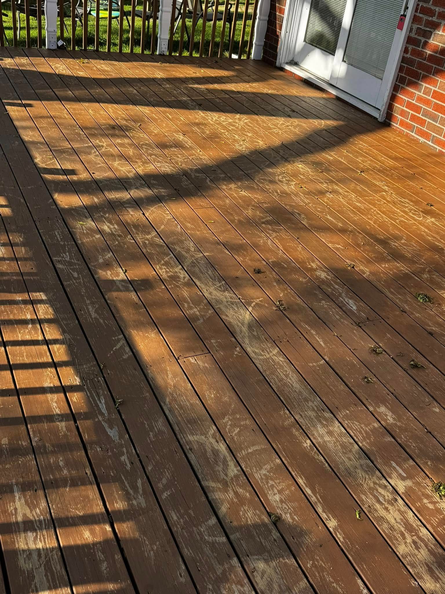 Sunlit wooden deck with railing shadows and an open white door leading outside