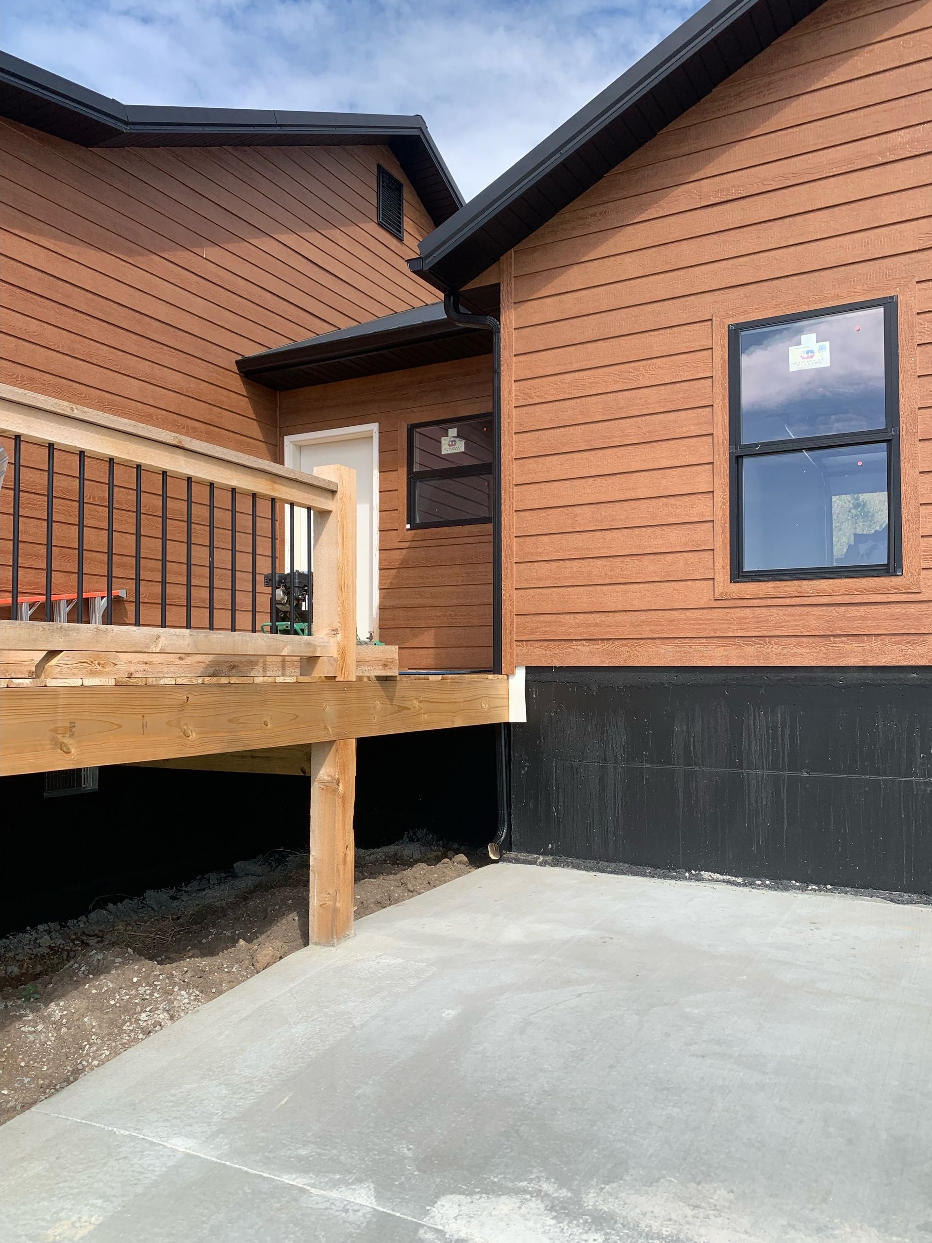 A brick house with a wooden deck and a concrete driveway