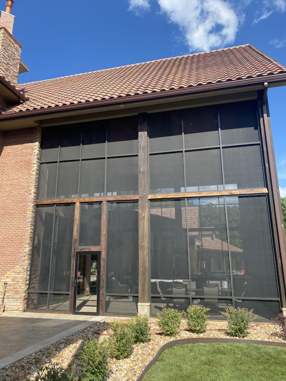 A large screened in porch with a brick building in the background