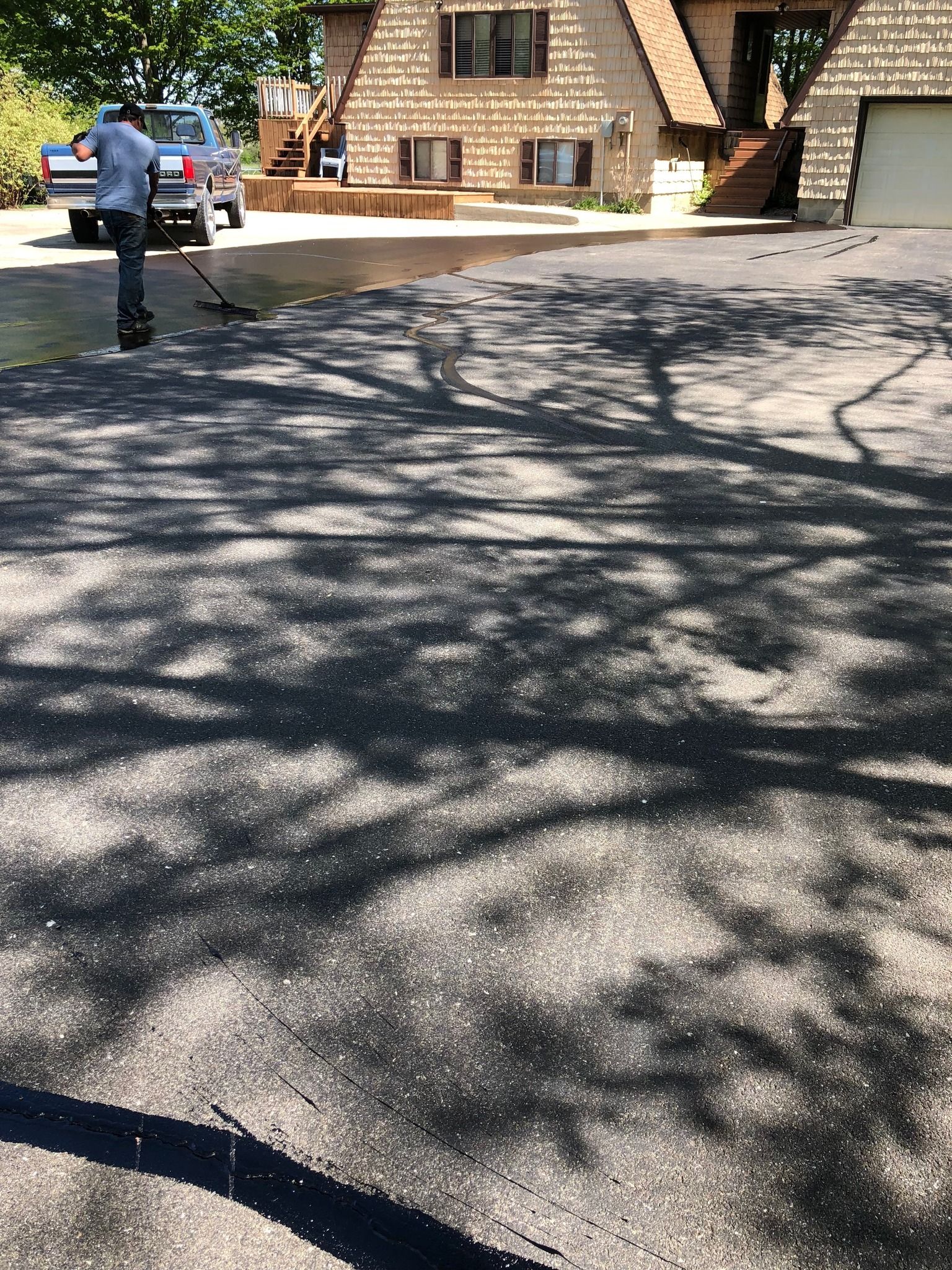 A man is standing in a driveway in front of a house.