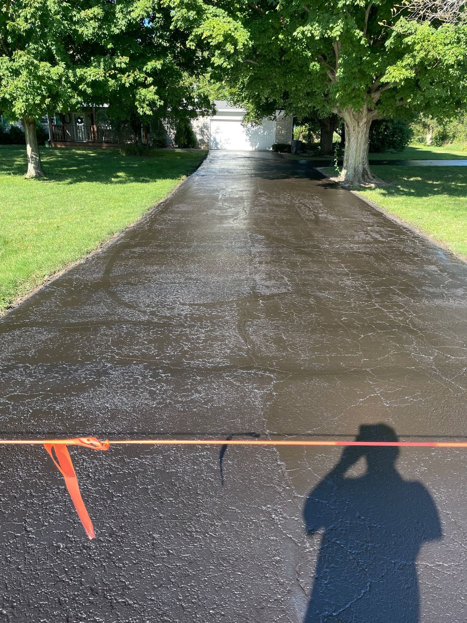 A person is taking a picture of a newly paved driveway.