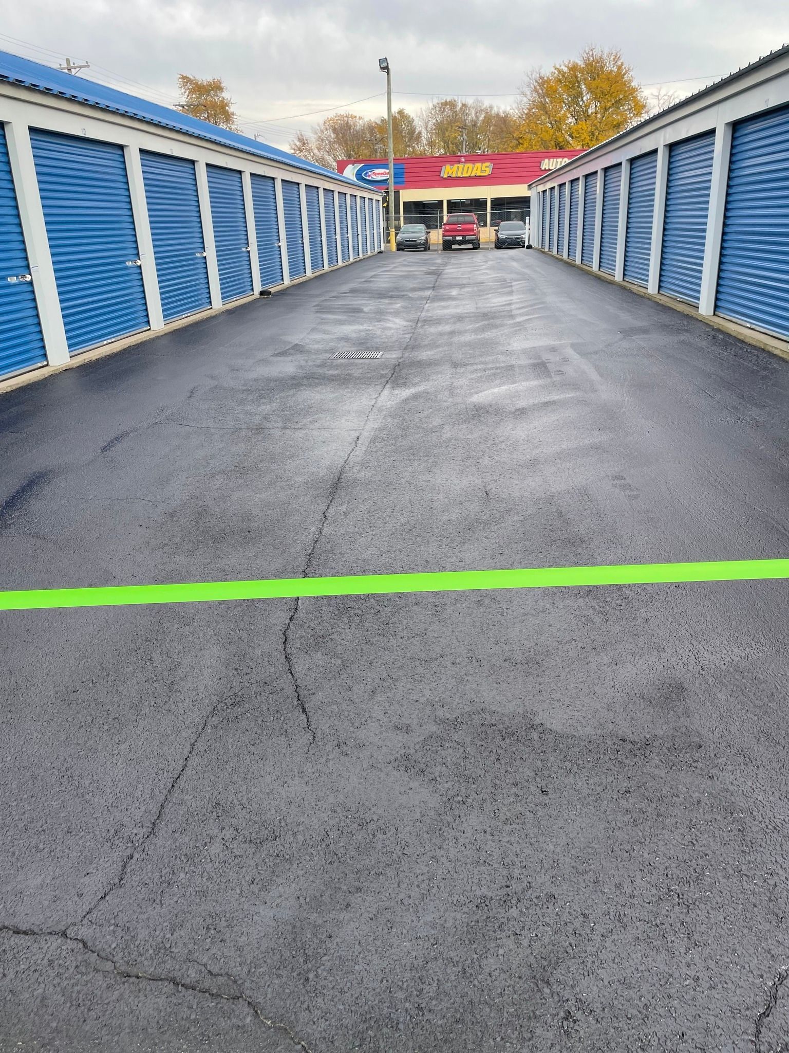 A row of storage units with a green line on the side of the road.