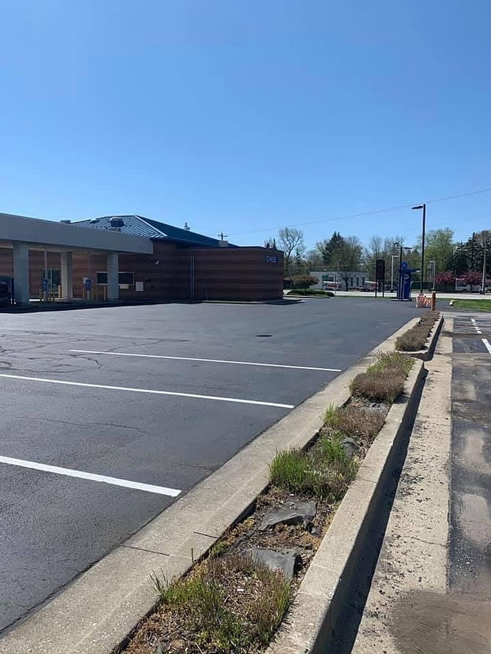 A parking lot with a building in the background on a sunny day.