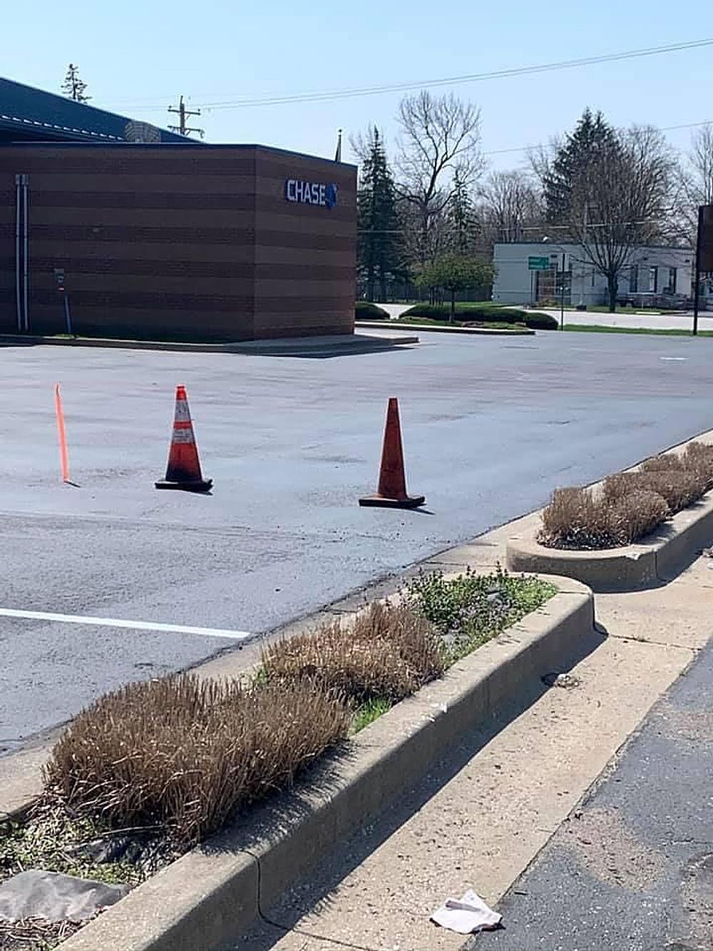 A parking lot with two orange cones in front of a building.