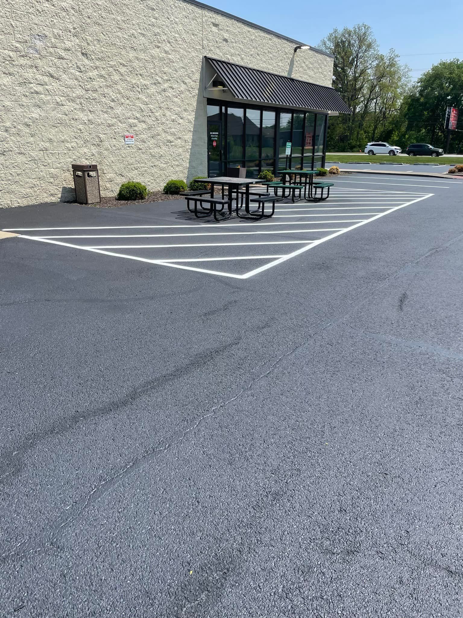 A parking lot with tables and chairs in front of a building.