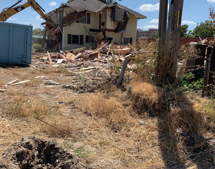 A house is being demolished by a cat excavator