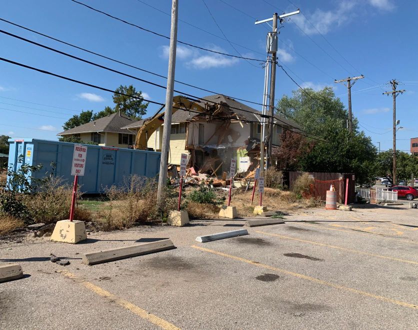 A house is being demolished in a parking lot.
