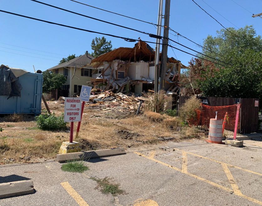 A demolition site with a handicapped sign in the foreground