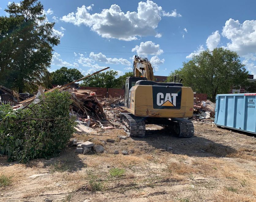 A cat excavator is being used to demolish a building.