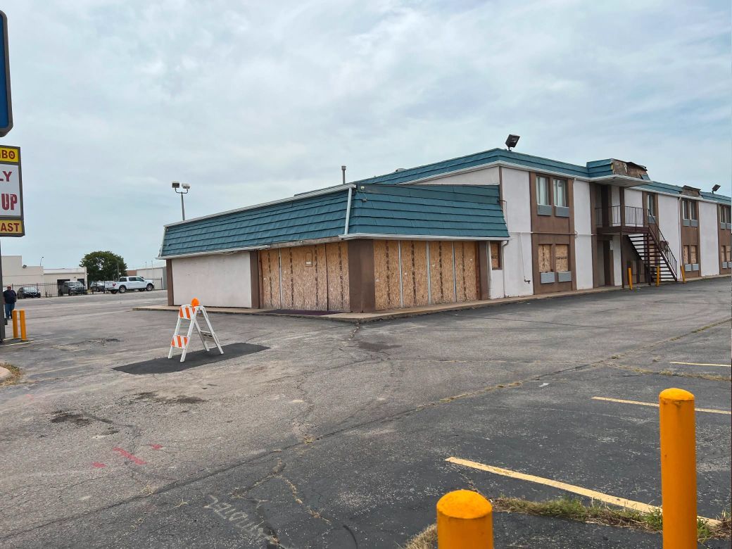 A building with a blue roof is sitting in a parking lot