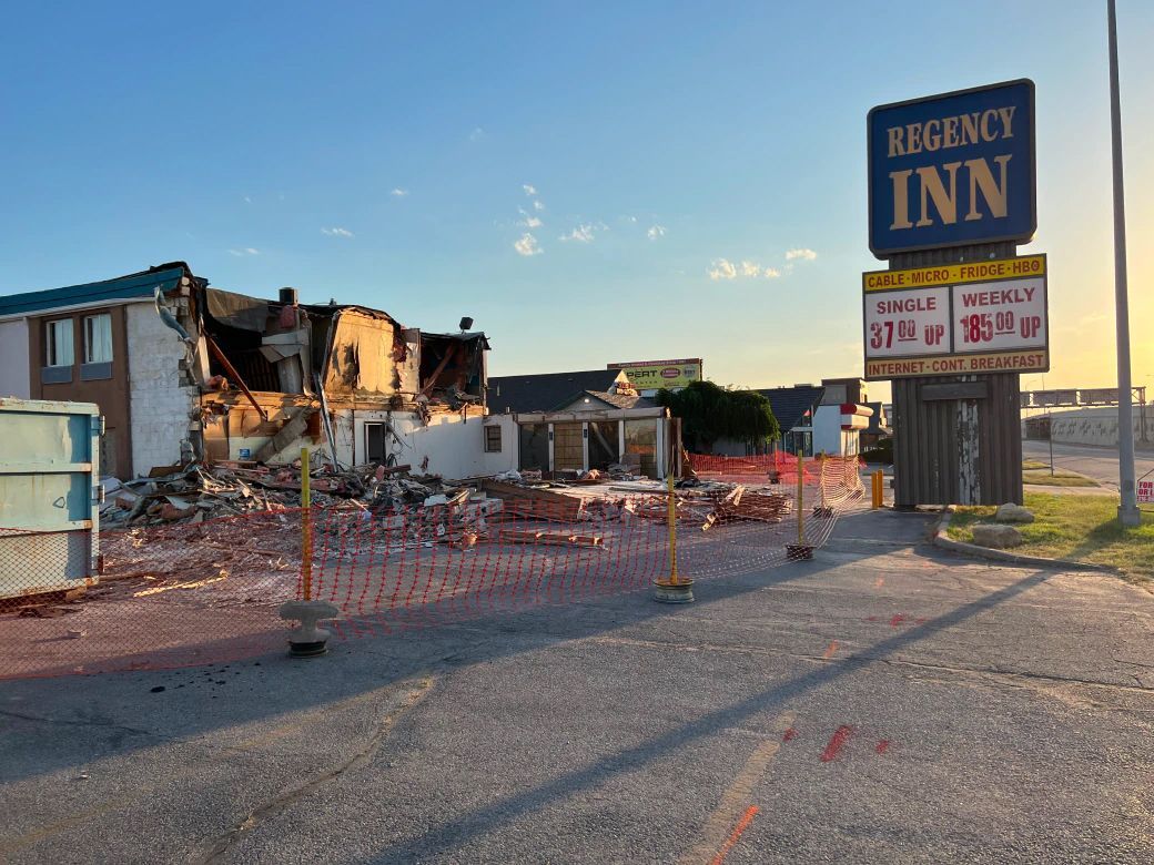 A motel is being demolished and a sign for regency inn is in the foreground.